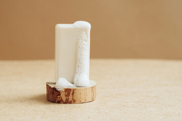 A piece of natural organic handmade soap with large foam bubbles on an abstract modern podium.