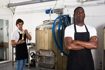 Fototapeta na wymiar Serious man brewer standing in beer factory during work, man on background