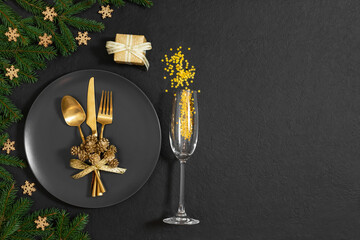Christmas table setting with golden festive decorations on black background. New Year party. Copy...
