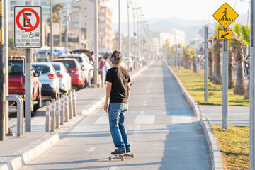 latin mature or senior man skateboard on bikeway in La Serena at sunset	