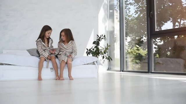 Two cute little girls in nightwear together at daytime in modern room
