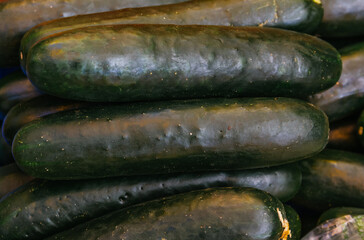 Green cucumbers stacked on a market stall.