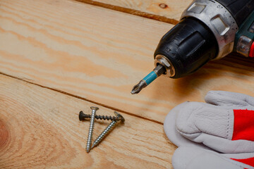 a screwdriver and construction gloves lie on the wooden flooring.construction works