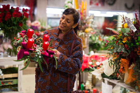 Positive peruvian middle age female shopping christmas decorations at flower shop