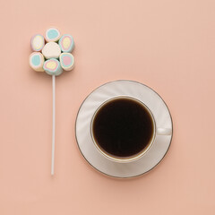 A cup of coffee and a multicolored marshmallow on a beige background. The concept of a fun breakfast. Flat lay.