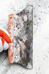 Qualified plasterer in protective glove using an dirty special spatula and scrapes concrete wall,...