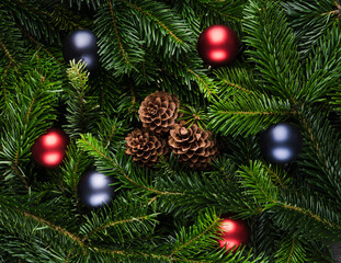 Obraz na płótnie Canvas Evergreen fir branches with pine cones and christmas balls. Christmas background. Shot from above.