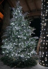 Beautiful Christmas tree decorated with silver ribbons, white lights and ornaments