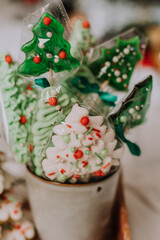 Christmas sweets, gingerbread painted with icing, lollipops and meringues in the shape of Christmas trees and tangerines on a beautiful tray. homemade cakes. delicious food for the winter holidays