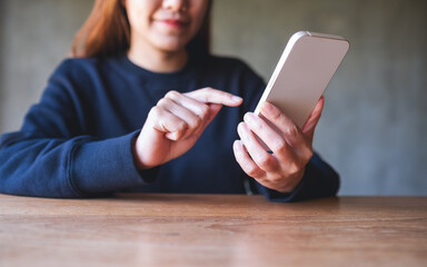Closeup image of a young woman holding and using mobile phone