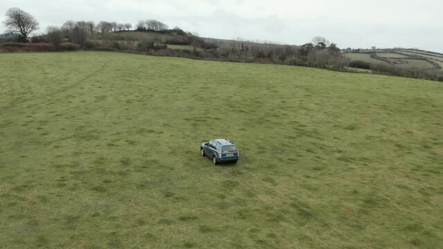 Pan follow aerial shot of farmer driving 4x4 around a field