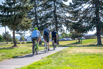 Naklejka premium Three cyclists enthusiasts for active healthy lifestyles ride in a column along the bike path