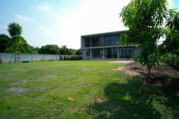 Exterior of house in modern style with grass field and garden at the backyard