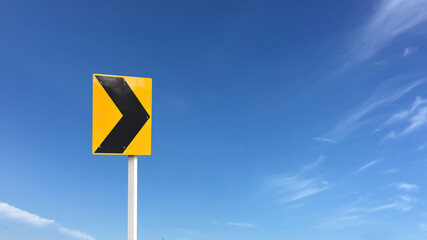 Right chevron traffic sign, this sign warns you of a change in direction or narrowing of the road. You may find these signs on the outside of a sharp curve or on approaches to a narrow bridge.