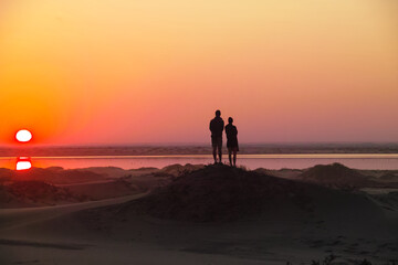 Fototapeta na wymiar Two people looking at a sunset/sunrise in the Namib desert