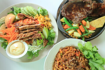 Lunch table with steak, grilled pork salad and spaghetti with tomato sauce recipe.
