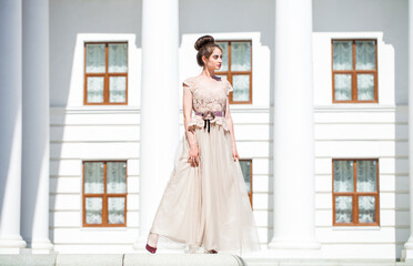 Young woman in a luxurious beige dress posing on the street