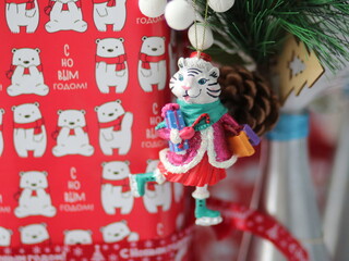 Christmas toy tiger with a bottle hanging on a spruce paw
