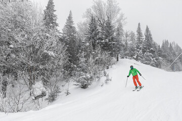 Winter Skiing. Alpine skier skiing downhill at mountain snow covered ski trail slopes in winter on perfect powder snow day while enjoying nature landscape