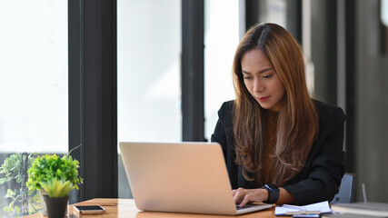 Attractive businesswoman working wit laptop computer in bright office.