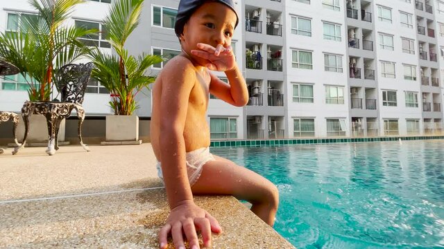 3-4 year preschool boy practice swim in swimming pool in condominium building sunset sky leisure boy