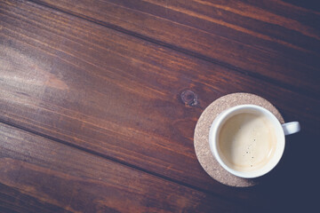 Cup of coffee with foam on wooden table, top view. Place for text