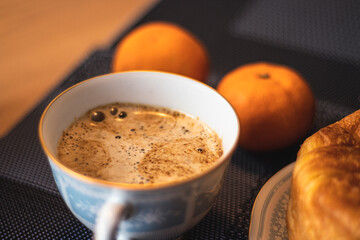 breakfast in blue and orange tones, puff butter bread with maple syrup and a cup of cappuccino, good morning mood and tangerines