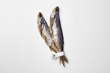 Two jerked or dried salted sabrefish with paper labels on tails isolated on white