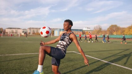 Young black girl in soccer training juggles the ball and throws it from one knee to another. Sports and active lifestyle concept