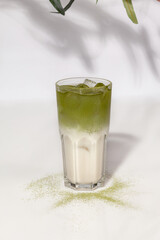 Glass of iced coconut matcha latte on white background