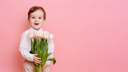 A happy boy gentleman holds a bouquet of delicate pink tulips in his hands. Space for your text, copy space