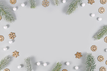 Fototapeta na wymiar Winter fir branches, snowballs and snowflakes forming border around gray background with copy space