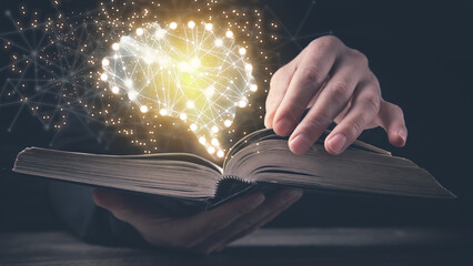 Man holding book with a human glowing brain.