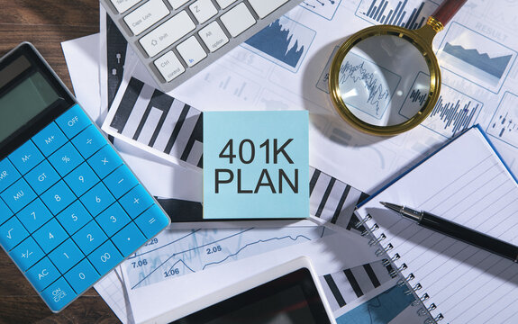 Text 401K Plan with tablet, keyboard, calculator, notepad and financial graphs.