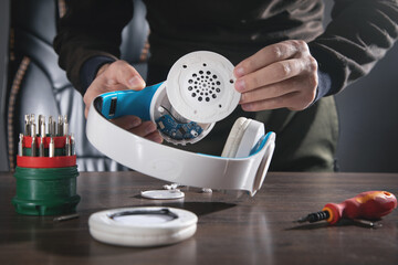 Man repairing white wireless headphones.