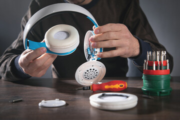 Man repairing white wireless headphones.