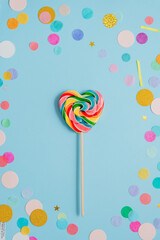 Multicolored heart shape lollypop on the blue background with confetti