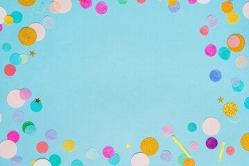 Frame of multicolored confetti on blue background with blank space for text