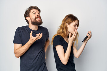 cheerful young couple in black t-shirts phone fun together friendship light background