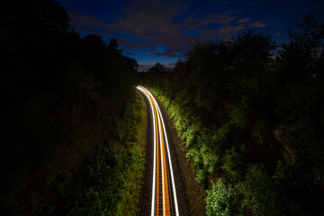 Night train draws a light trail over the railroad tracks