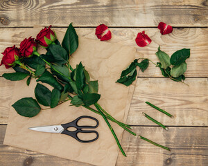 The florist creates a floral arrangement of roses, pruning the stem with scissors.Festive mood.