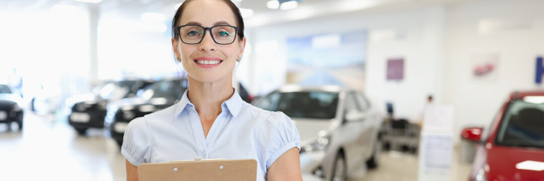 Woman manager consultant stands in car showroom closeup