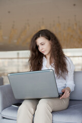 Fototapeta premium Young woman working on laptop in the public pplace. Caucasian woman with brown hair in the office and using laptop