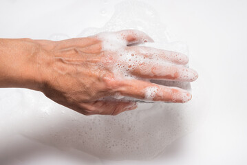 Hand with foam holding sponge, on white background