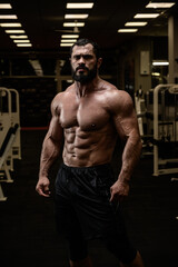 Fototapeta na wymiar strong young male with beard and perfect fitness abdominal muscles in sport gym in night