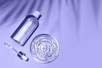 Very peri color of the year 2022. Trendy concept. Antibacterial, hyaluron gel bottle, pipette and transparent cosmetic serum smear on violet background.
