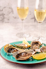 Opened fresh oysters on a blue plate, served with lemon and ice.