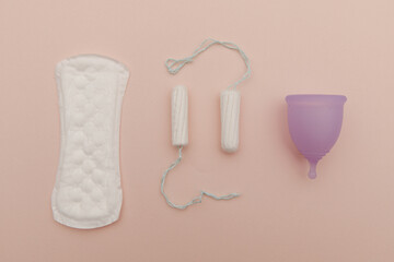 Pad, menstrual cup, tampon on a pink background. Concept of critical days and hygiene. Top view