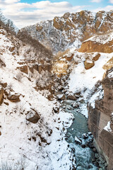 Fototapeta na wymiar Fast mountain river in the gorge at winter season