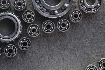 Flat Lay steel deep groove ball, roller and tapered bearings on a gray structural surface with space for text. A set of bearings for heavy equipment and mechanical engineering with copy space.